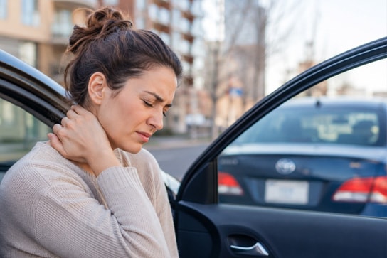 A person holding their neck in discomfort after a car accident, representing neck pain following a motor vehicle collision in Calgary